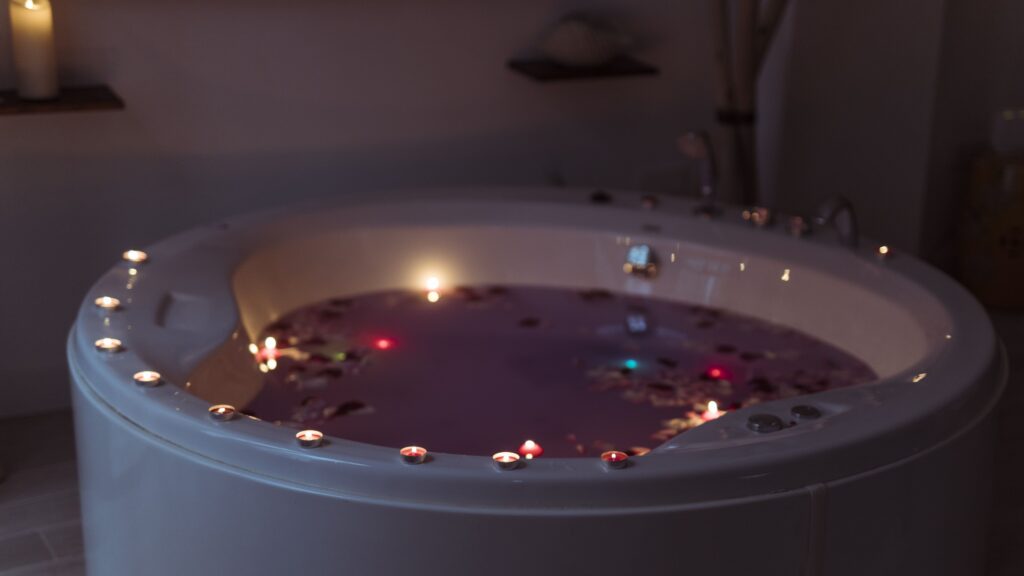 In-room hot tub decorated with candles and flower petals for a romantic evening experience